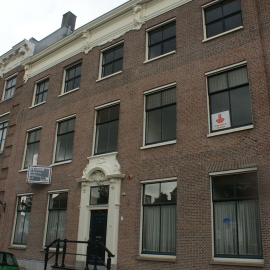 Statig patriciershuis, beneden deels verbouwd, aangebrachte brede ramen, deuromlijsting rococo, rechte kroonlijst met gesneden consoles, Louis seize deur en stoep