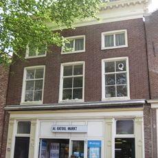 Pand met voorgevel met geblokte kroonlijst onder hoog schilddak met halfronde dakkapel en topschoorsteen