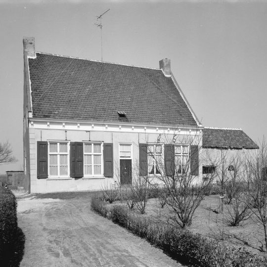 Dorpswoning onder dwars, met pannen belegd zadeldak tussen zijtopgevels. In de gepleisterde voorgevel Empire schuiframen en jaarankers