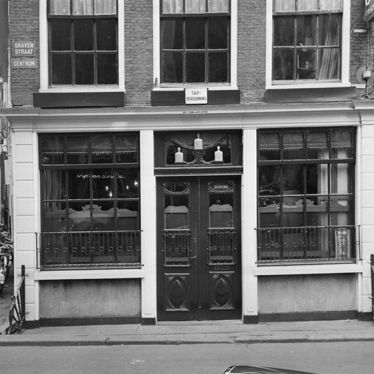 Hoekhuis met klokgevel en pui waarin gesneden deur en snijraam