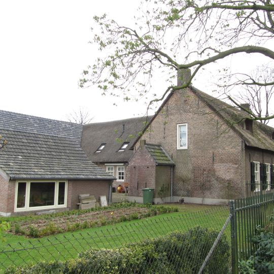 Boerenwoning onder rieten zadeldak en voorzien van ramen met kleine roedenverdeling