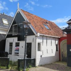 Gepleisterd huisje met puntgevel met houten voorschot en versierde topmakelaar