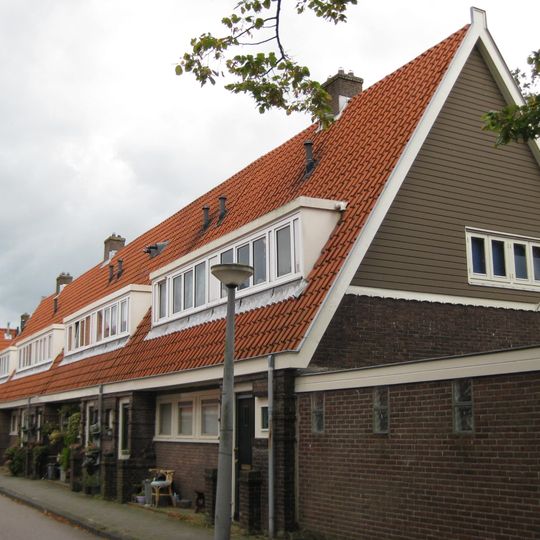 Blok met 8 keukenwoningen, zo genoemd vanwege destijds nieuwe plaatsing van keuken aan de voorzijde, aan de zijkant een houten topgevel, bouwstijl Amsterdamse School.