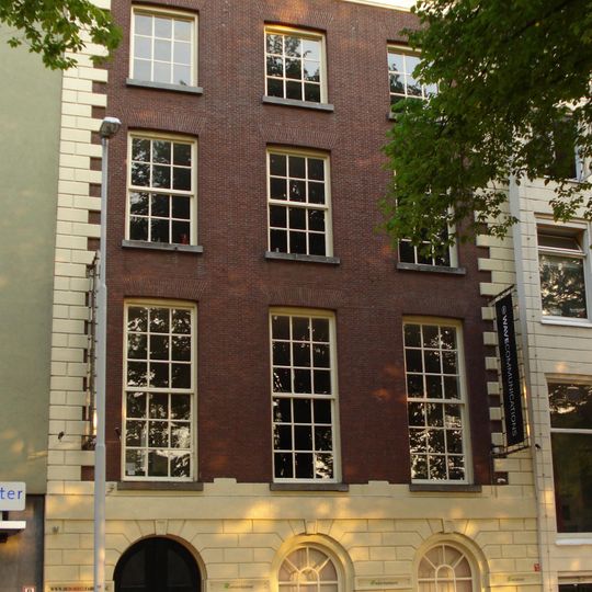 Koopmanshuis. Eenvoudige lijstgevel met gebosseerde pui en hoekkettingen. In de pui getoogde vensters en deur. De vensters van de bel-etage en de verdiepingen hebben 18-12- en 9-ruitsschuiframen