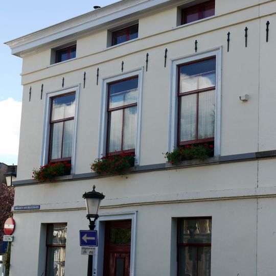 Pand, gepleisterd, met verdieping en mezzanino onder flauwhellend, met pannen gedekt zadeldak met schild aan linkerzijde