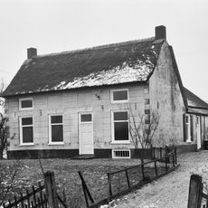 Gepleisterde boerderij; Rieten zadeldak; gesneden deur